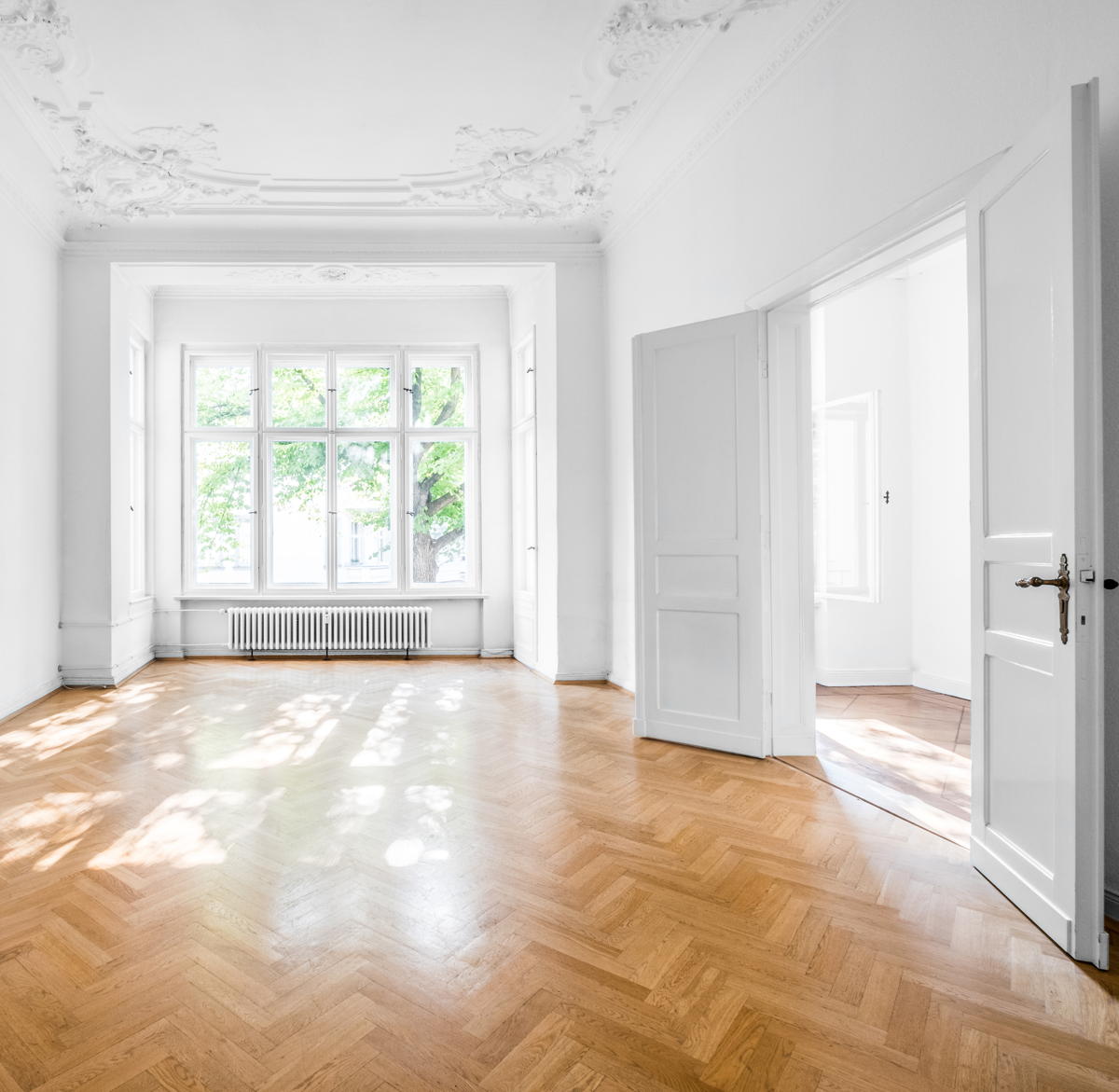 Eine weiß gestrichene Altbauwohnung mit Parkettboden.